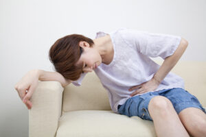 お腹をおさえる女性
